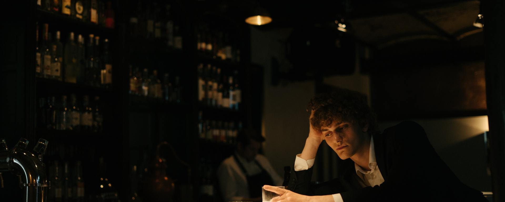 Hombre solo en la barra del bar, frente al vaso vacío