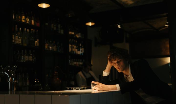 Hombre solo en la barra del bar, frente al vaso vacío